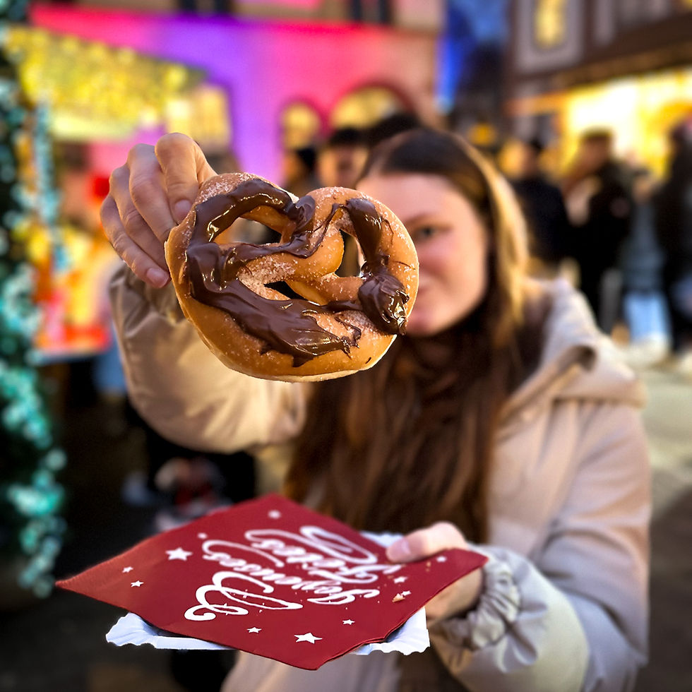 young woman holding up a chocolate covered pretzel