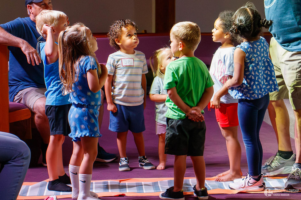 Group of young children gathered, Grace Kids, inside with adult supervision.