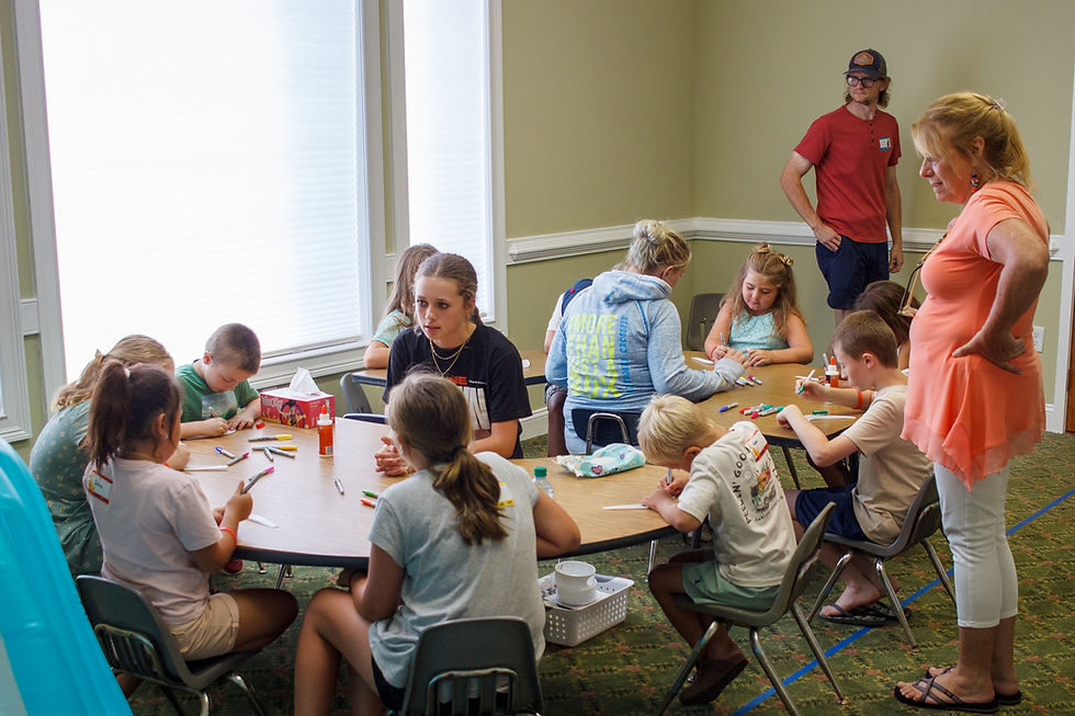 Children and adults at a table doing crafts or art. Grace Kids