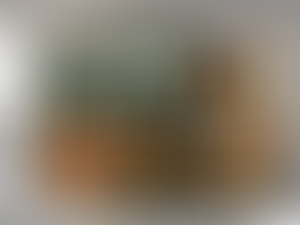 A teacher stands at the front of a classroom holding a book labeled “Teacher Manual,” reading from it while three students sit at desks looking bored, tired, or disengaged. The classroom is muted and industrial-looking, with green chalkboards and rows of desks. Superimposed text reads “Mass-Producing Learning: The Hidden Cost to Teachers and Students,” and the Joyful Learning Collaborative logo appears in the bottom-right corner.