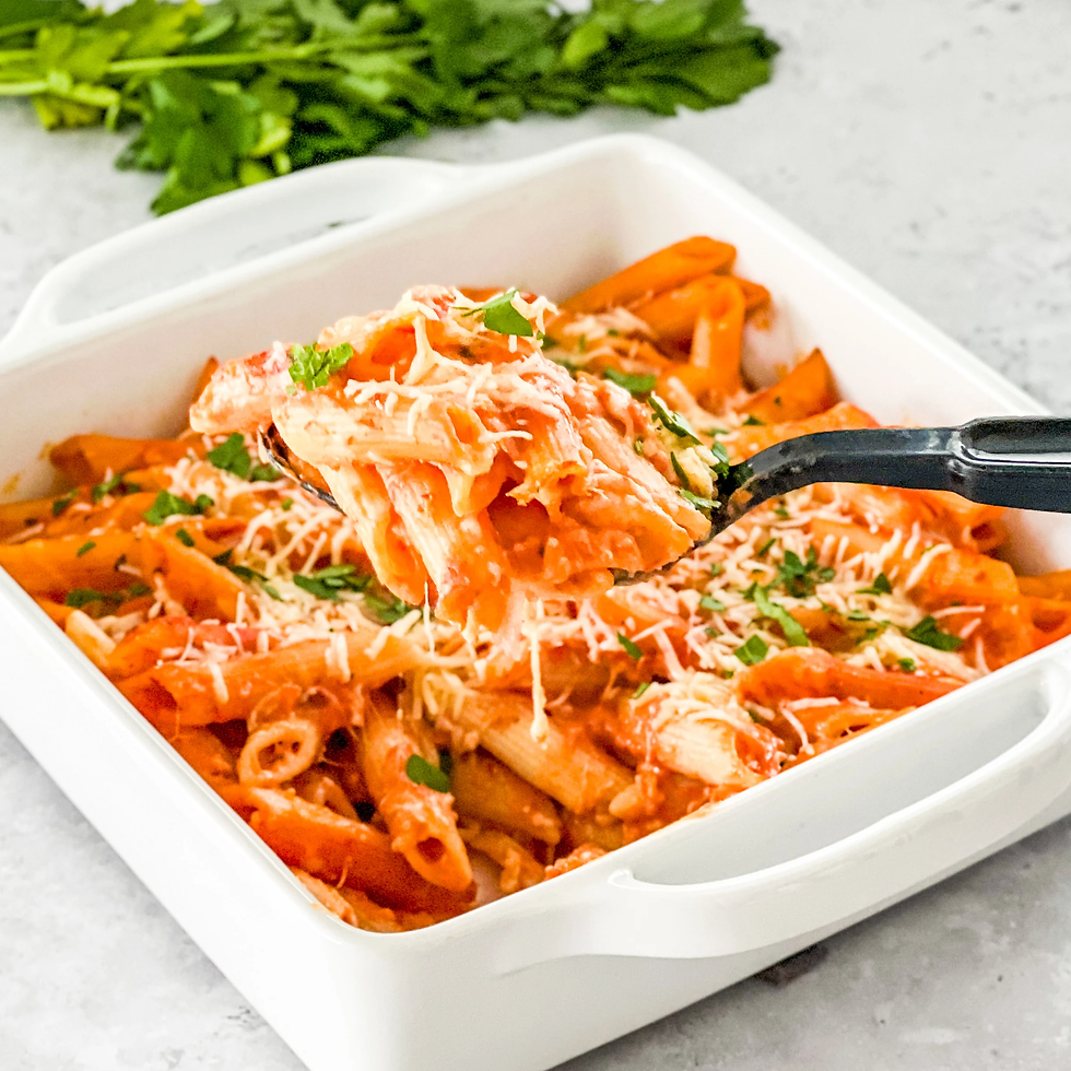 Penne pasta in creamy tomato sauce topped with cheese and herbs in a white dish. Black fork lifting a portion. Green leaves in background.