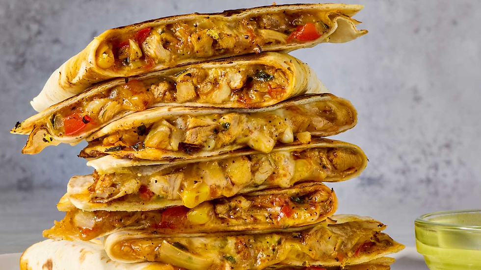 Stack of grilled quesadillas filled with chicken, corn, and bell peppers. Visible melted cheese, with a small dish of sauce nearby.