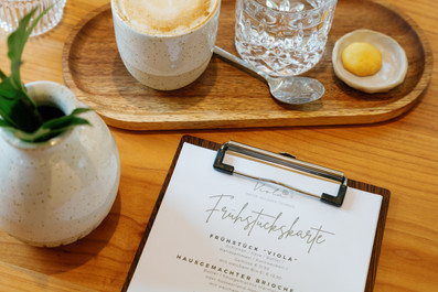 Eine Speisekarte, ein Glas Wasser und ein Kaffee auf einem Holztisch. 