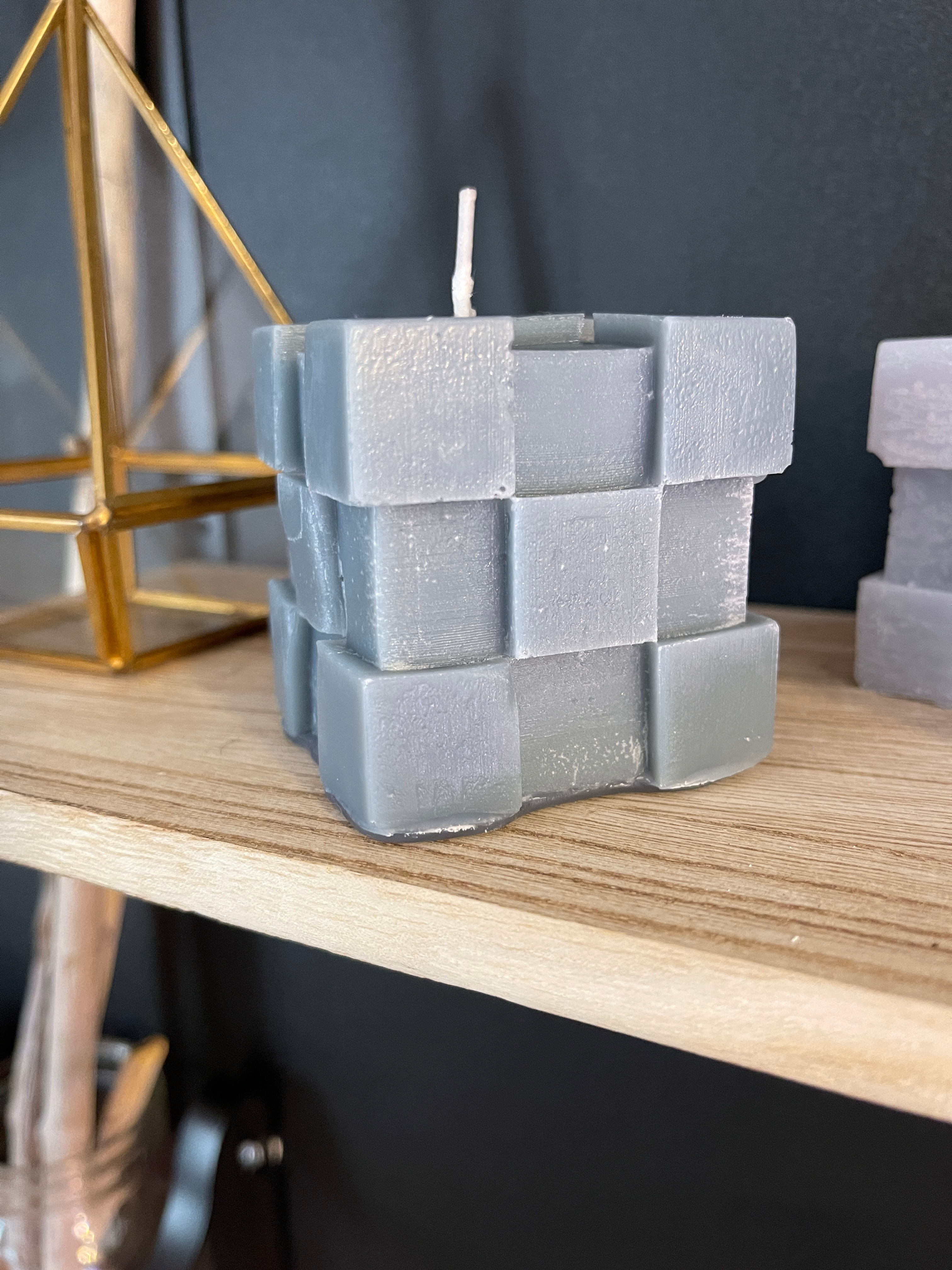 Bougie grise carrée sur étagère en bois Bougies Janie Créati pour décoration.