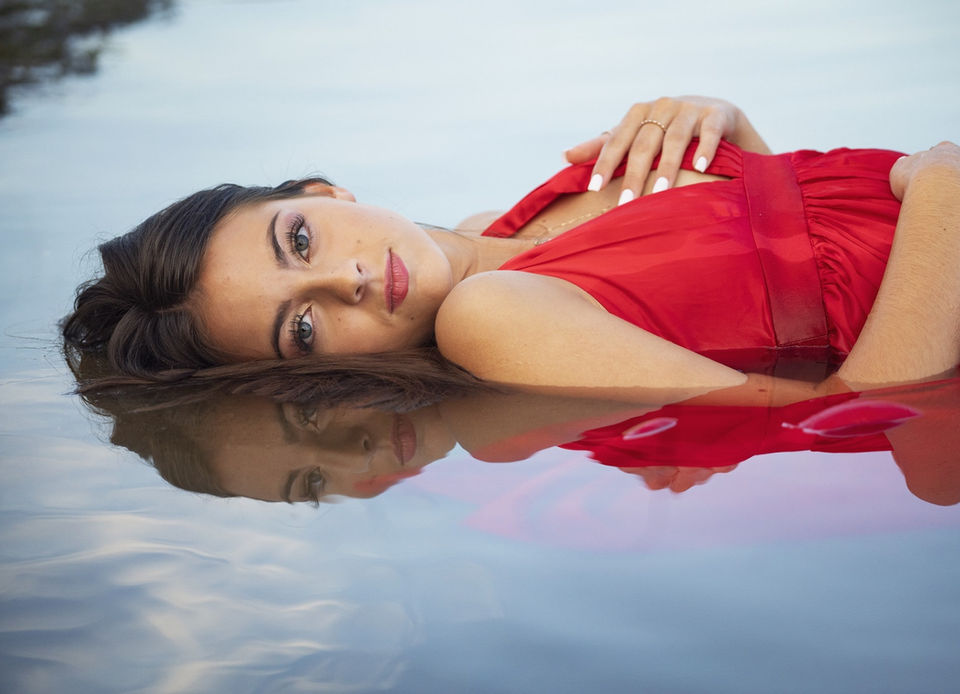 Graceful Beauty KC High School Senior with hair and makeup laying in a bed of water