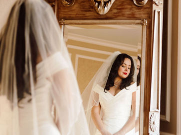 Graceful Beauty KC Bride with hair and makeup done staring into mirror. www.gracefulbeautykc.com