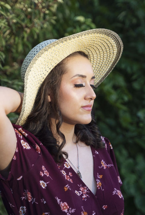 Graceful Beauty KC High School Senior with hair and makeup done in a field embracing the sun setting on her face.