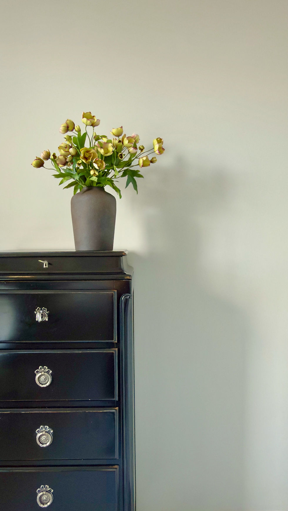 Thumbnail: soft yellow hellebores in black vase arrangement