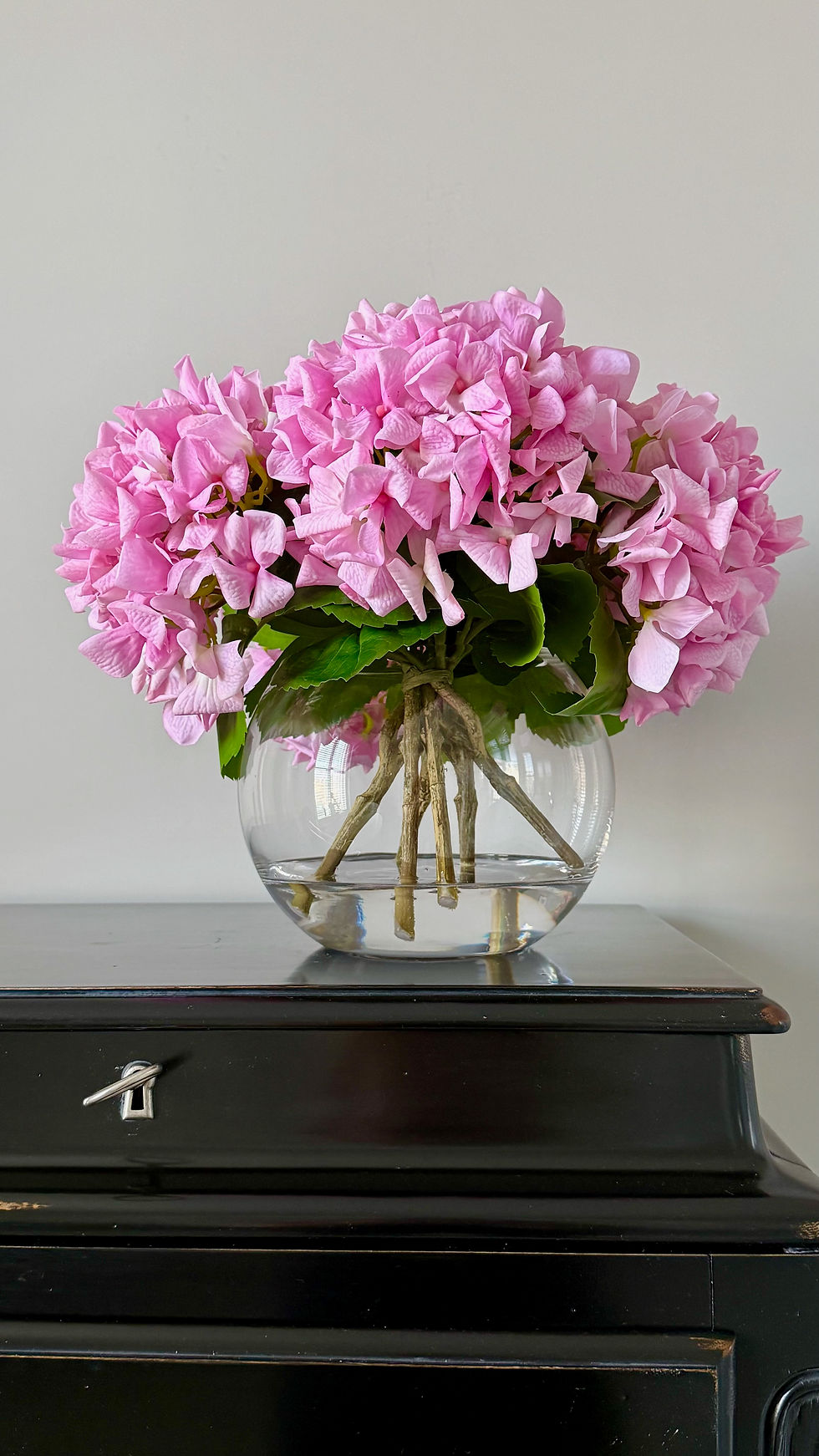 pink real touch hydrangeas set in faux water arrangement in gold fish bowl vase in stylish setting by whispering lily