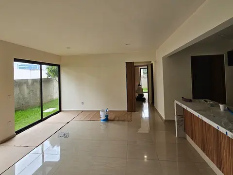 Departamento en etapa final de acabados, mostrando la amplitud de los espacios, pisos cerámicos brillantes y la calidad de la carpintería en la barra de cocina.