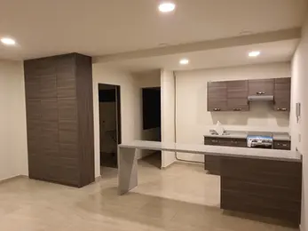 Cocina moderna de concepto abierto en departamento, equipada con barra de granito, gabinetes de madera oscura y acabados minimalistas.