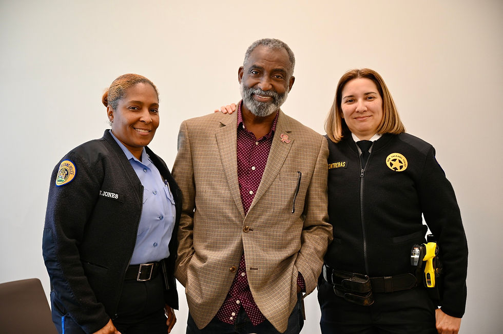 Two female officers and a man smiling, standing together.