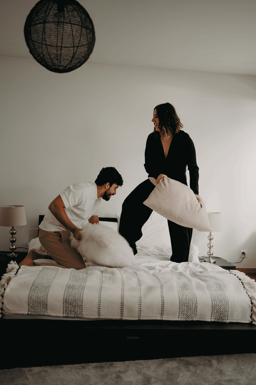 Bataille de coussins lors d'une séance couple lifestyle à la maison.