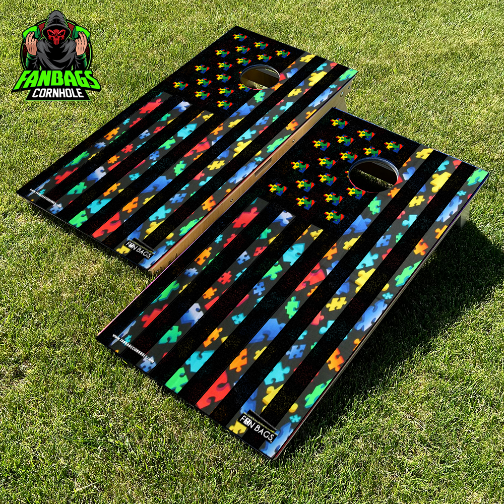 a set of cornhole boards sitting in grass with an autism awareness design