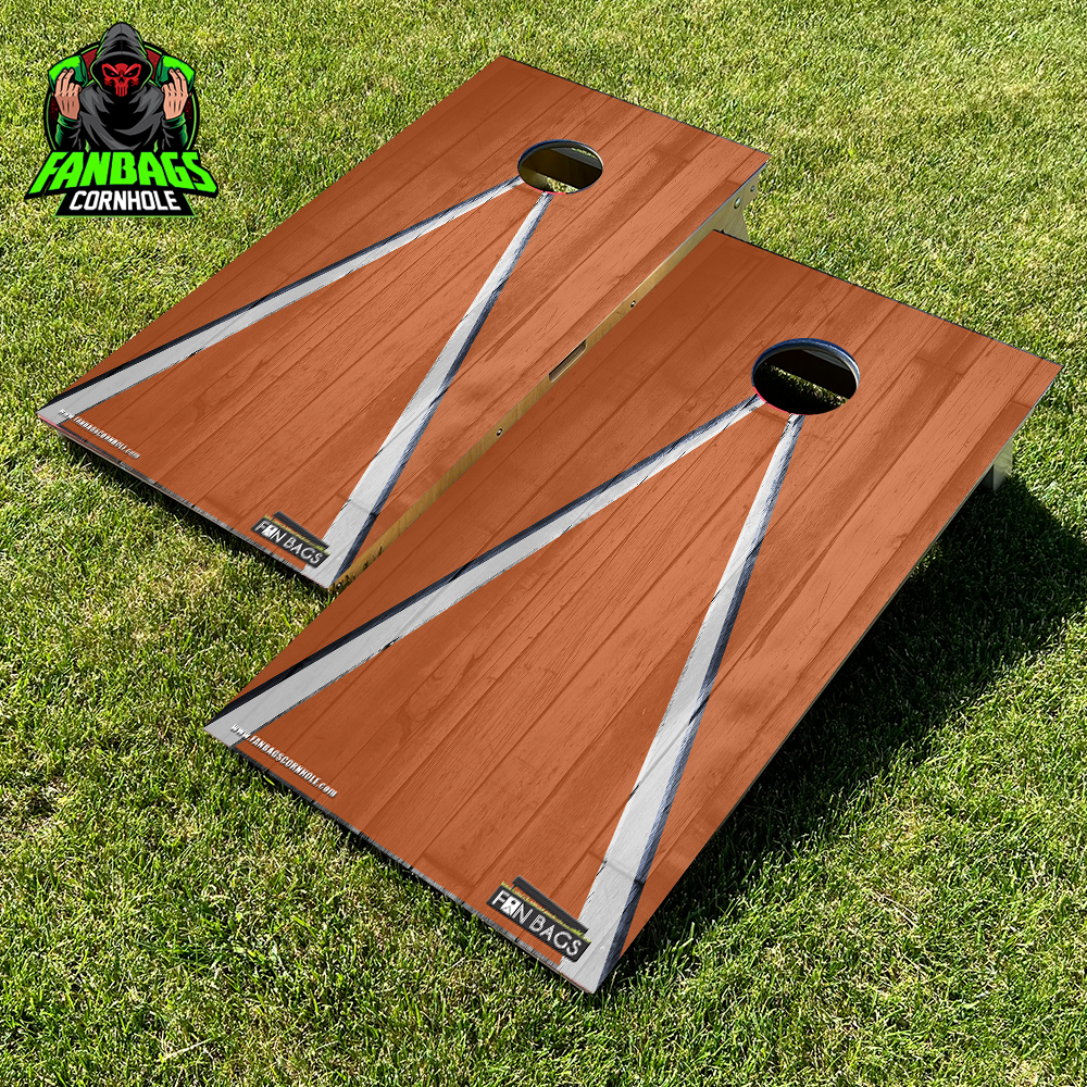 a set of cornhole boards sitting in grass with an orange and white triangle design