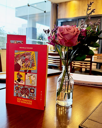 o livro aos prantos do mercado em cima da mesa ao lado de uma flor