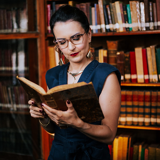 vania albarracin em frente a uma estante de livros lendo um livro