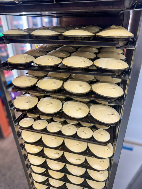 A tempting display of unbaked pies at Mairangi Bay Bakery, neatly stacked in a tray and filled with a variety of delicious ingredients, eagerly awaiting their turn in the oven to transform into warm, flavourful delights.