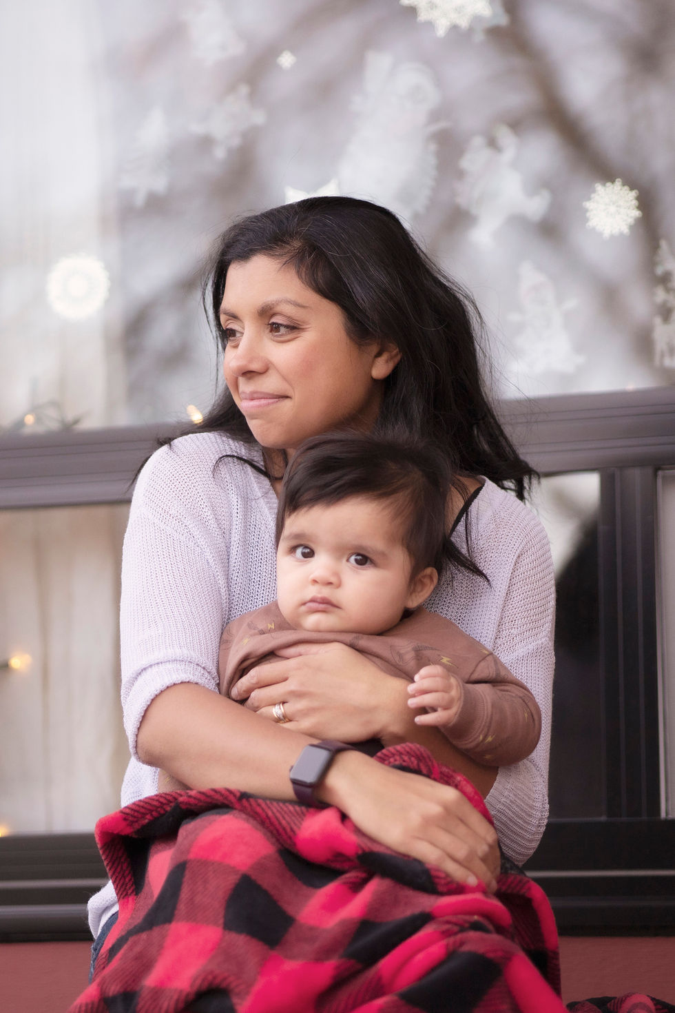 a young mother sits in front of her house with her little son in her arms