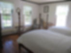 The second bedroom in the Susan suite has two twin four-poster beds and three bright windows.
