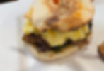 A breakfast sandwich with charred roasted red onions, cheesy scrambled eggs, and basil-sriracha sauce