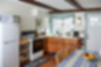 The Jenny cottage kitchen has a fridge, stove, sink, and coffee maker. There is also a kitchen table