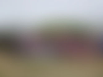 A group on men stand in front of a rugby goal post holding a sign.