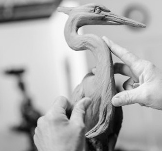 Close-up photo of the hands of Artist Geoffrey C Smith sculpting a clay bird.