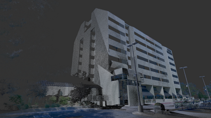 Angled view of a multi-story building showcasing its unique architectural design with angular features. The image is rendered in low light, emphasizing the structure's details and the surrounding environment, including nearby lighting fixtures.