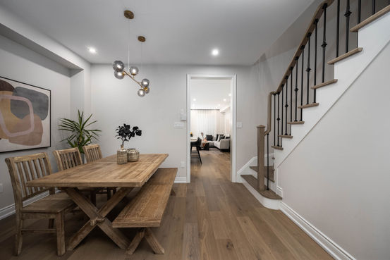 Modern dining room with wood table, benches, and staircase.
