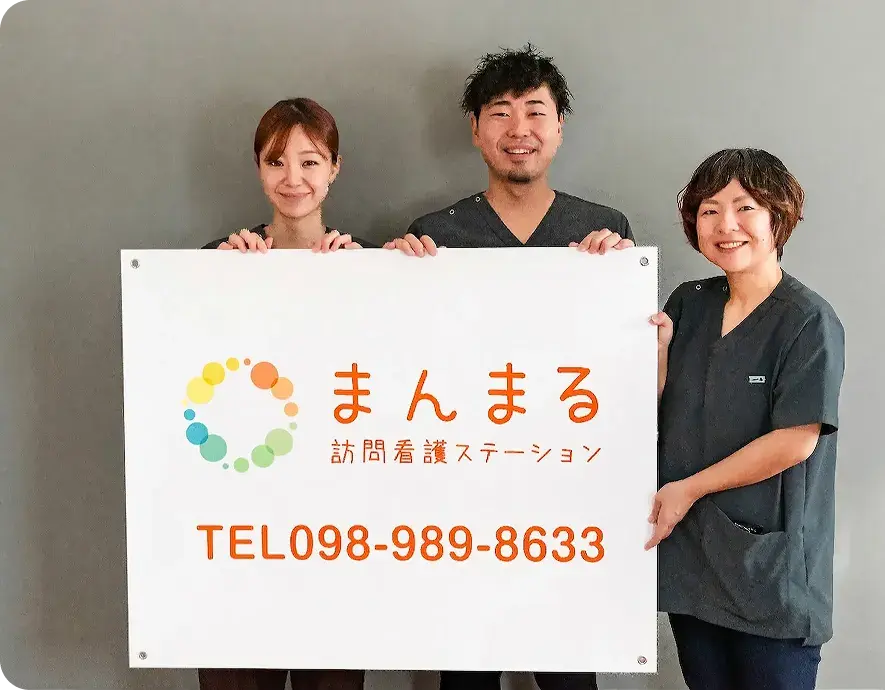 まんまる訪問看護ステーションの看板を前に持つスタッフ