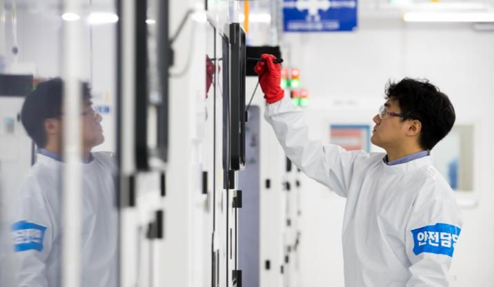 A semiconductor scientist in a clean-room suit examining a microchip under specialized laboratory lighting.