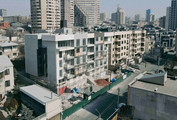 Aerial view of a residential building under construction in Yerevan, Armenia, surrounded by city streets and nearby apartment buildings.
