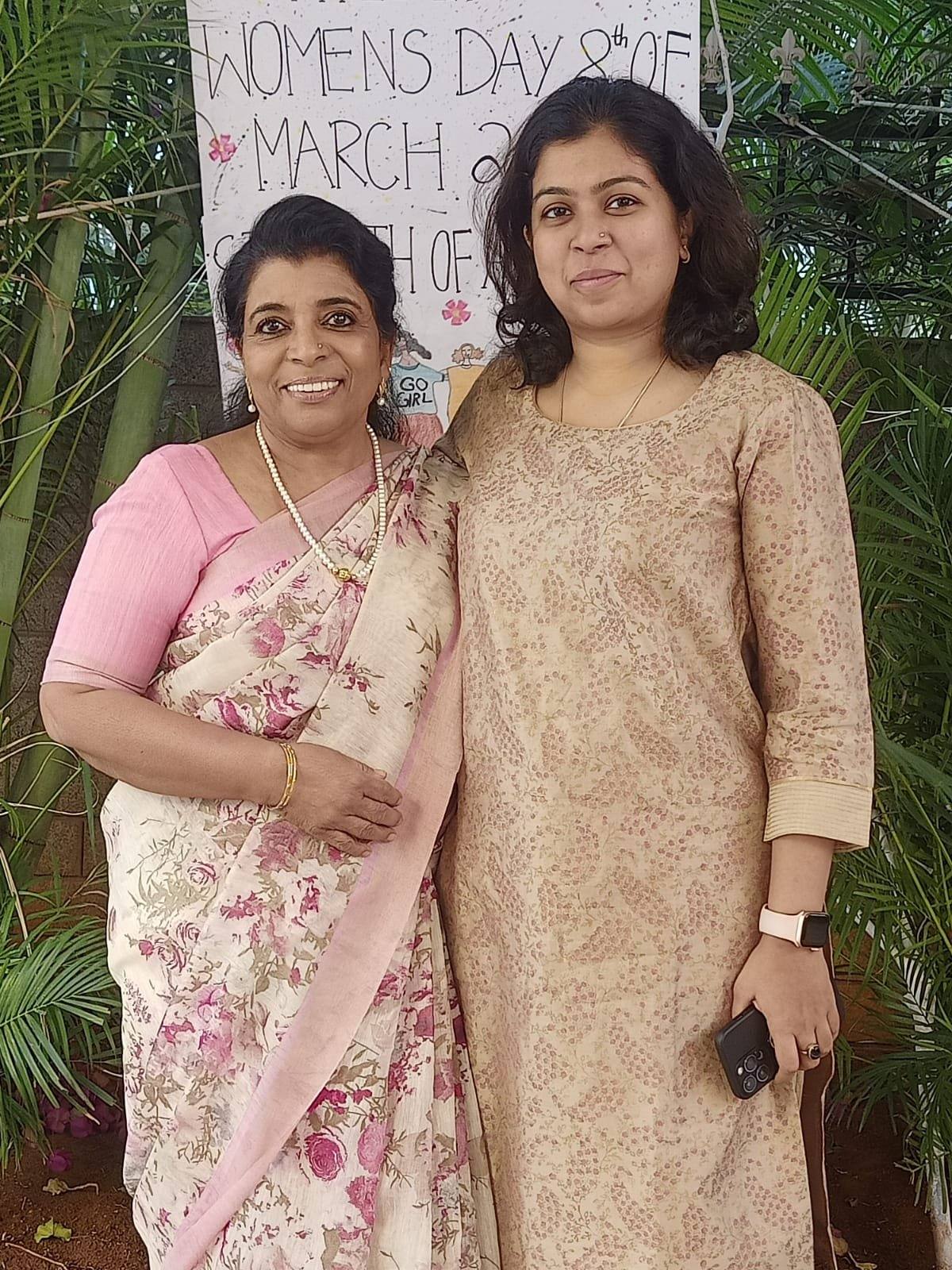 Sanjana Rathi con la anfitriona junto al banner del Día de la Mujer