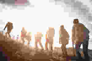 Der Artikel heißt: Backpacking statt all-inclusive – die Reise auf die New-Work-Insel. Das Bild zeigt siebenjunge Personen, die im Sonnenuntergang auf einem Berg Backpacken.