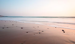 Tranquil ocean waves on a sandy beach at sunrise, symbolizing calm, grounding, and healing.