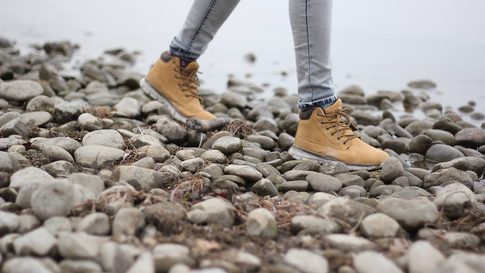 Close-up of a foot walking on a rocky path, symbolizing how unprocessed trauma feels like carrying rocks in your shoe.