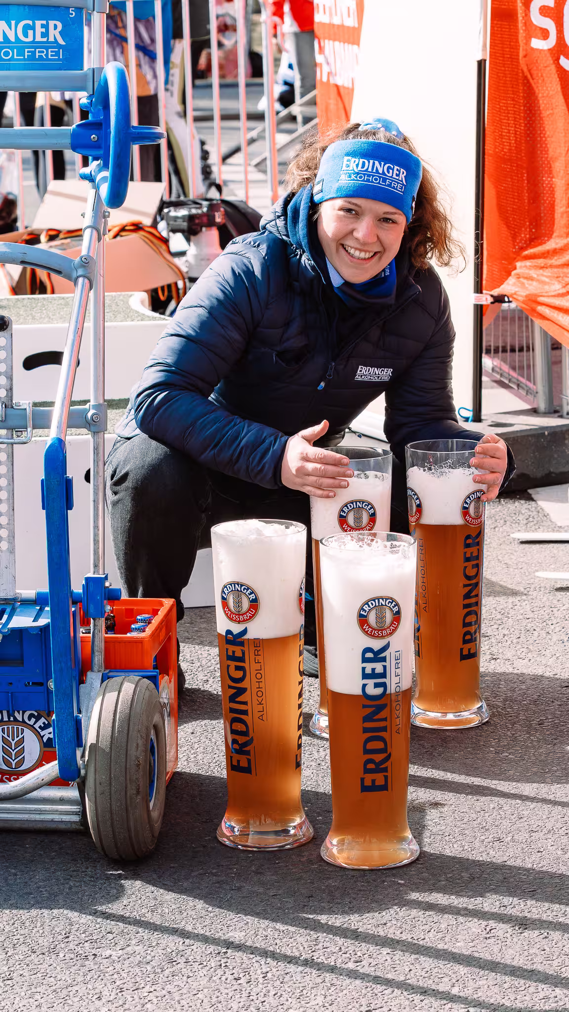 A smiling person posing with large Erdinger Alkoholfrei glasses at the Berlin Half Marathon 2026.