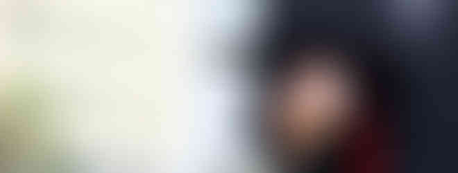 Graduate holding a black mortarboard with a red tassel; education achievement. Premium Visa Solutions.