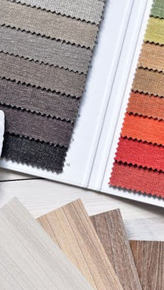 Various fabric swatches including cotton, linen, polyester, silk, wool, rayon, and denim neatly arranged side by side, showcasing textures and colors to highlight different types of clothing materials.