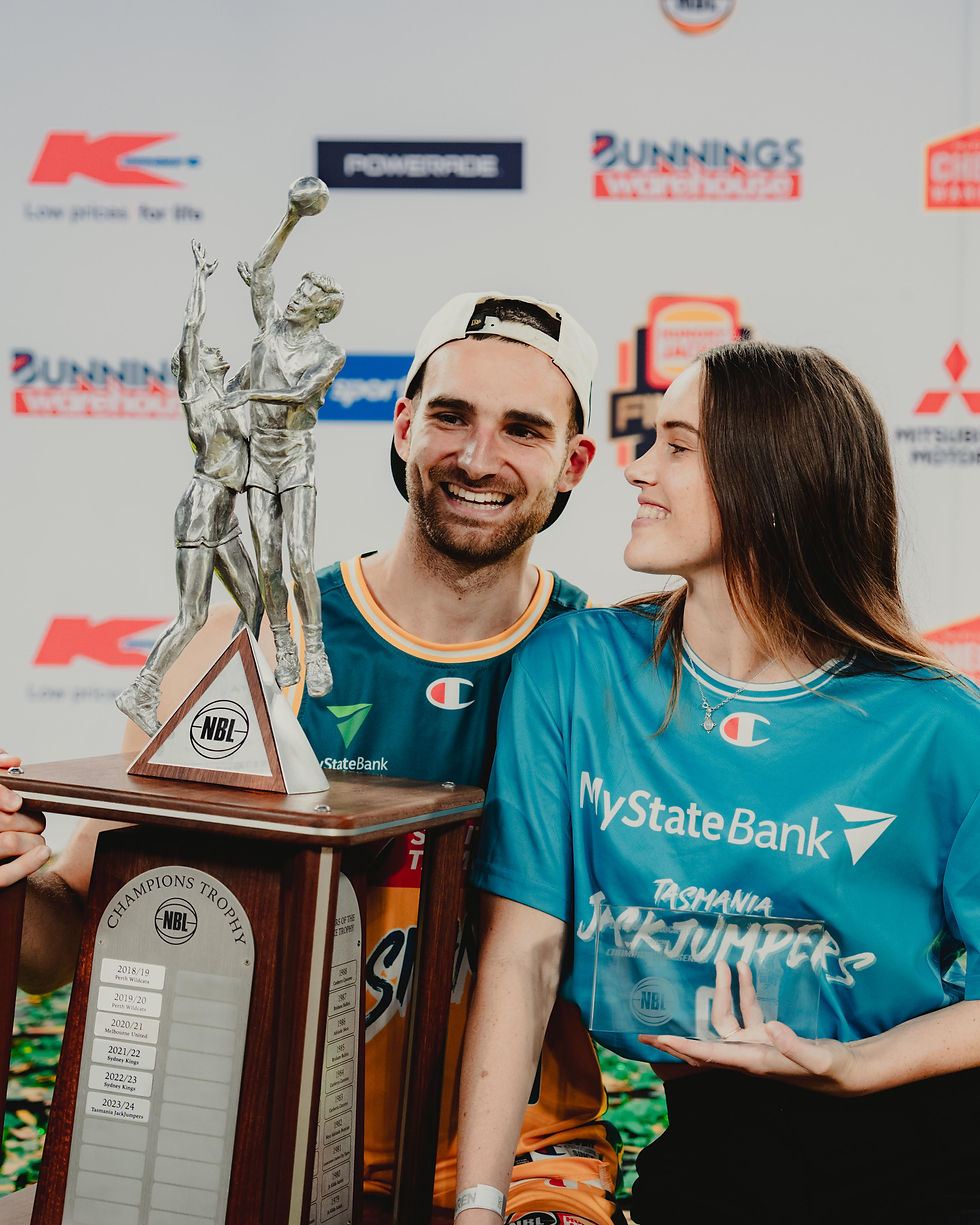 Jack McVeigh and fiancé Bethany Heaft holding the NBL Championship Trophy and Finals MVP award.