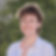 Ames Gersten, a therapist specializing in working with adult-identified Autistic people and LGBTQ+ community members, smiles welcomingly while standing outside in a white loose-fitting button-down shirt. 