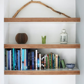 Floating timber shelves mounted on white wall with books and decorative items
