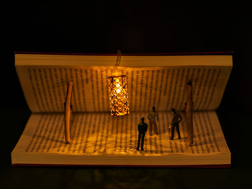 Imagem conceitual de um livro aberto com miniaturas de pessoas interagindo em seu interior, iluminado por uma pequena lanterna, simbolizando a técnica show, don't tell na escrita.