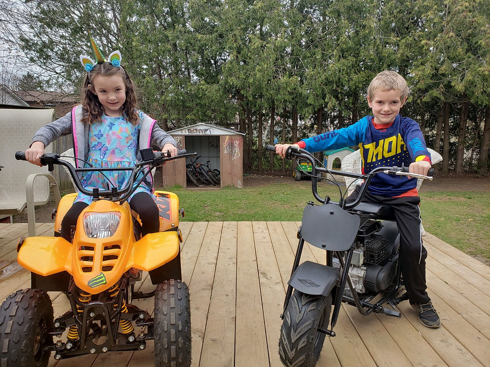 a boy and a girl sitting on an atv and a minibike