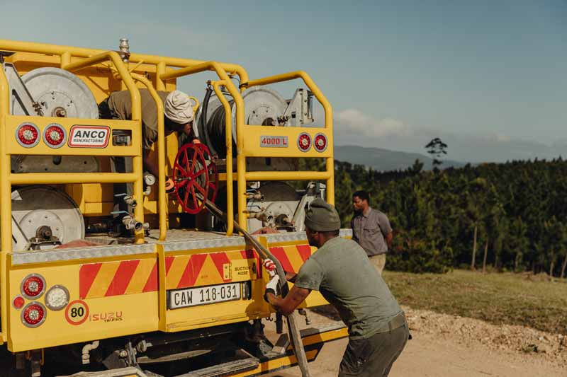 Competitor pulling a firefighting hose from a fire truck during a practical challenge