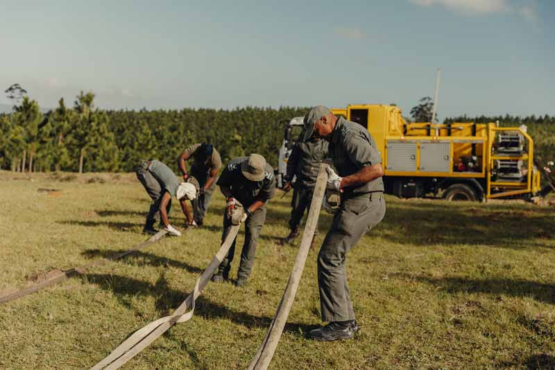 Competitors pulling canvas hoses during a practical firefighting challenge