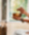 A person is holding a singing bowl and is about to strike it. There is incense during in a holder next to them.