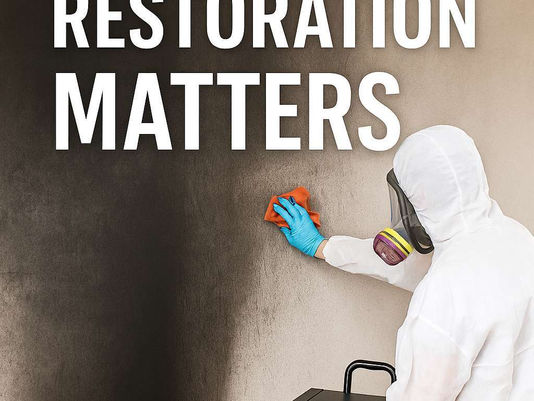 Technician in protective gear cleaning soot-stained wall with cloth and air scrubber, overlaid text reading “Fast Fire Restoration Matters"