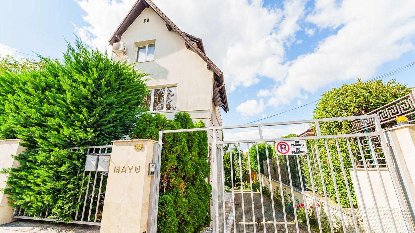 Exterior of MAYU clinic in Cluj-Napoca with front gate, green trees, and building facade.